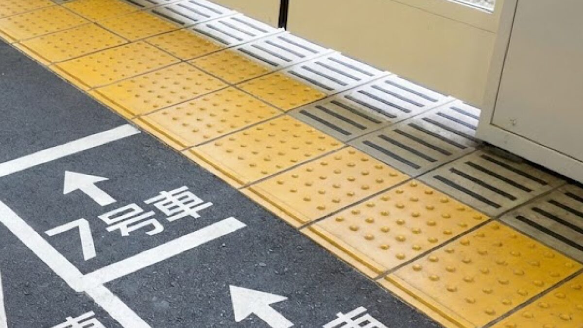新大阪駅のホームで電車の乗車位置案内（号車番号）を確認している旅行者の手元と足元のイメージ