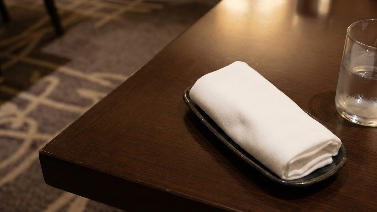 落ち着いた照明で、布のおしぼりとガラスのコップが置かれたテーブルセット